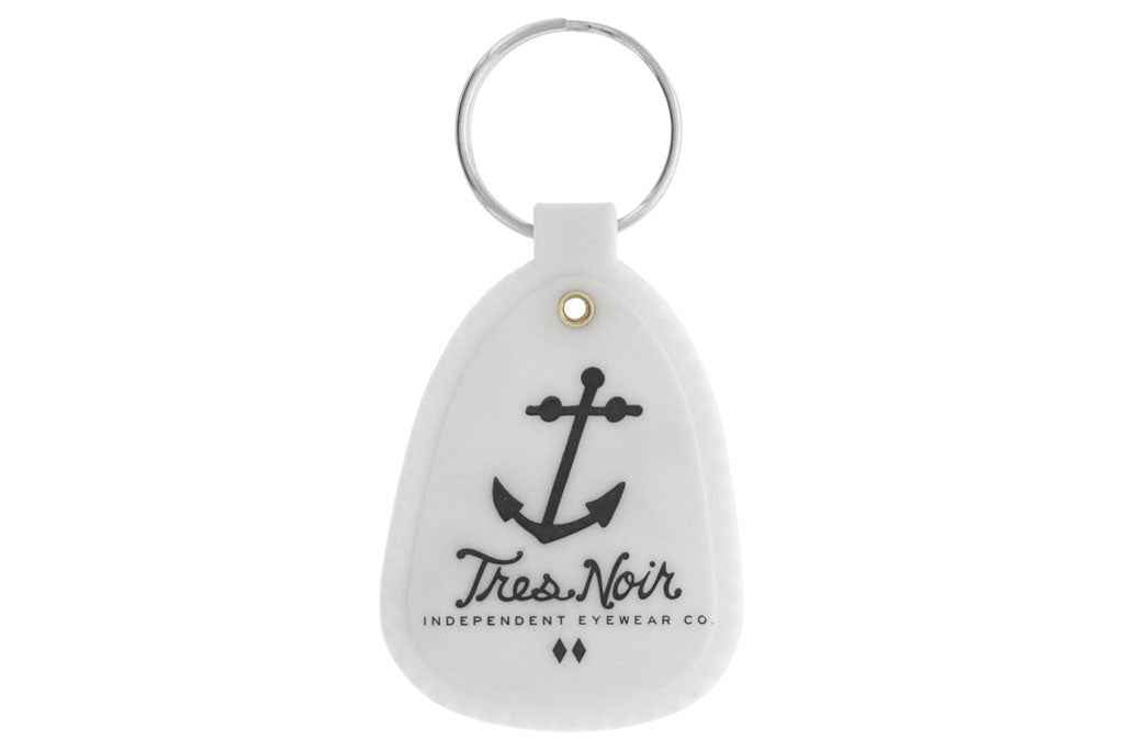 White glow in the dark saddle key chain with Tres Noir anchor logo and script logo on front