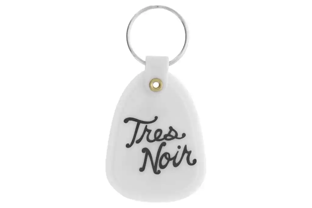 White glow in the dark saddle key chain with Tres Noir script logo on back