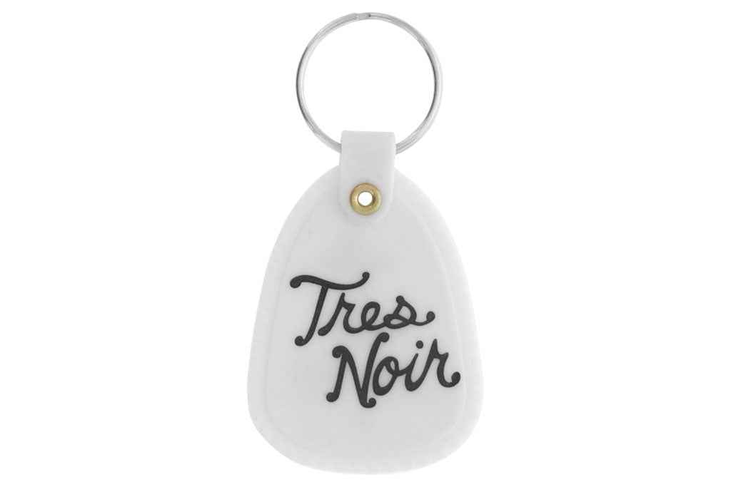 White glow in the dark saddle key chain with Tres Noir script logo on back