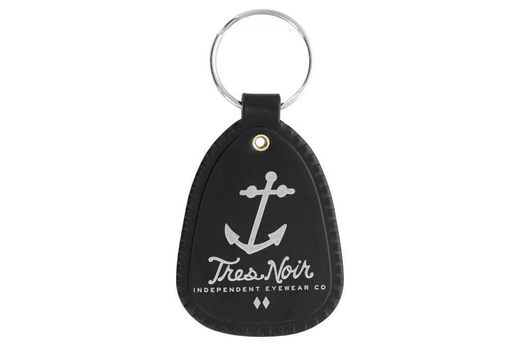 Black saddle key chain with Tres Noir anchor logo and script logo on front