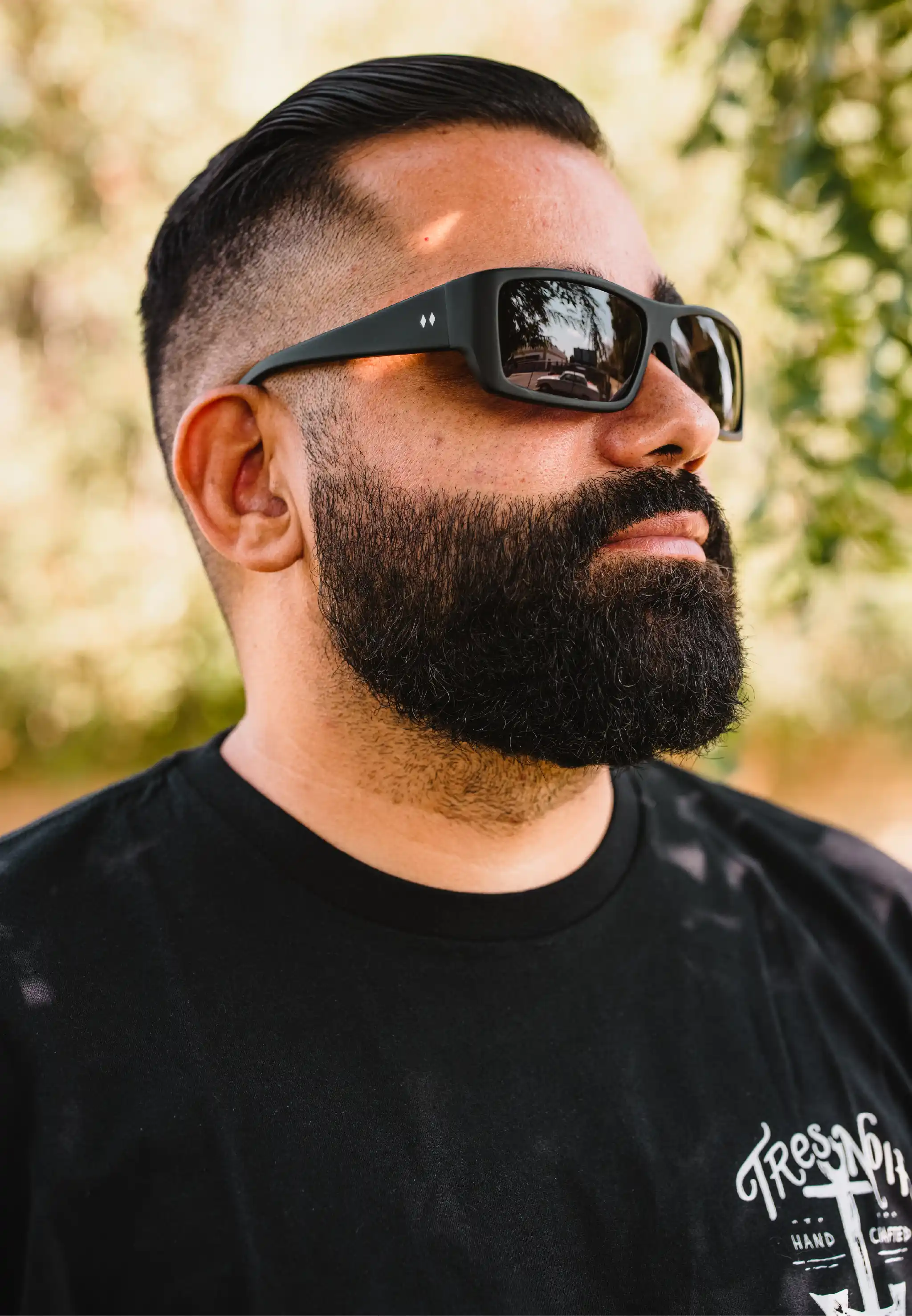 Man holding matte black Bronson sunglasses